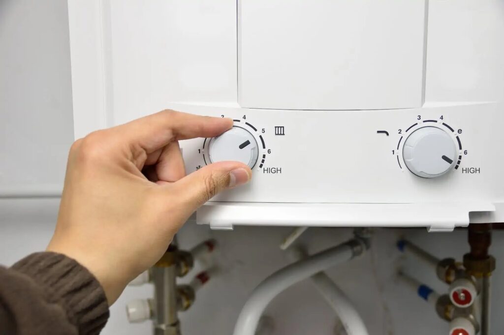 Person's hand adjusting their water heater's temperature setting