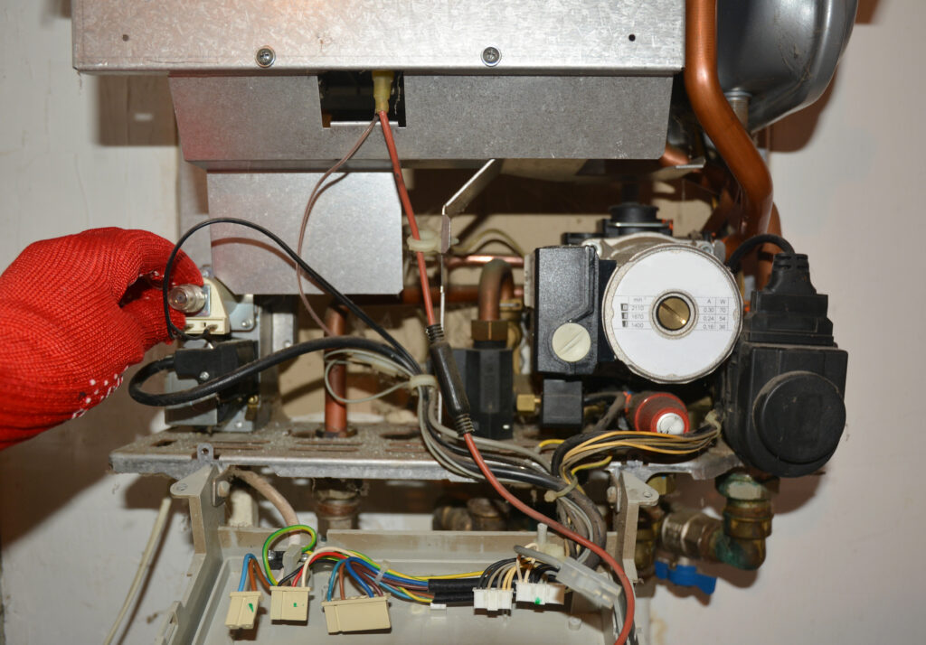HVAC technician servicing a boiler that has internal components exposed